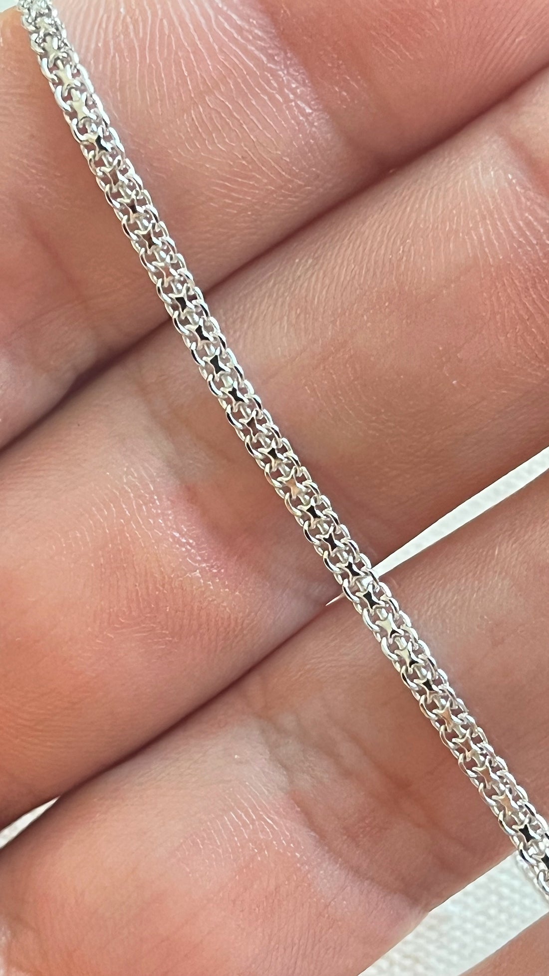 Bracelet chaîne Tank en argent rhodié, maille plate de 2,2 mm, tenu dans la main